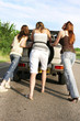 Three women pushing a car