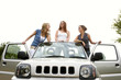Three women posing on a car