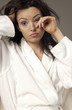 Woman in white bathrobe rubbing her eyes 