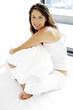 Woman sitting on the bed hugging a pillow 