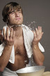 Shirtless man splashing water onto his face 
