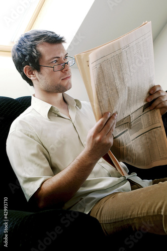 Photo: Bespectacled man reading newspaper Bespectacled man reading newspaper