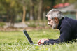 Man lying on the grass using laptop