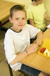 Boy looking at the camera with his lunch box on the table