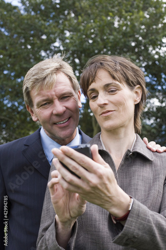 Photo: Businessman and woman looking at handheld device Businessman and woman looking at handheld device