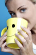 Woman drinking from a cup with smiley face