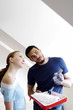 Foto: Man discussing with his girlfriend while holding a paint roller and a tray Man discussing with his girlfriend while holding a paint roller and a tray