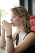 A teenage girl sipping hot tea carefully while looking out of the cafe