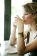 A teenage girl sipping hot tea carefully while looking out of the cafe