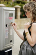 A teenage girl inserting coin into the parking meter