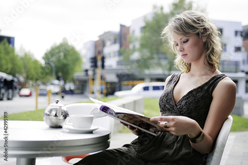 Photo: A teenage girl reading a magazine at an open air cafe while waiting for her friend A teenage girl reading a magazine at an open air cafe while waiting for her friend