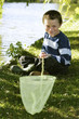Photo: Young boy sitting by the lake side holding fishing net Young boy sitting by the lake side holding fishing net