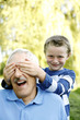 Photo : Young boy covering his grandfather's eyes Young boy covering his grandfather's eyes