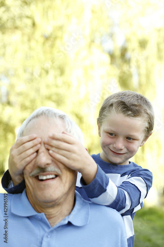Photo: Young boy covering his grandfather's eyes Young boy covering his grandfather's eyes