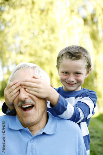 Photo: Young boy covering his grandfather's eyes Young boy covering his grandfather's eyes