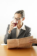Businesswoman drinking wine while reading newspaper