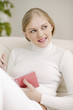 Young woman sitting on the couch holding organiser and pen
