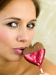 Woman biting a heart-shaped chocolate