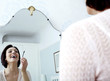 Woman looking at the mirror, applying make-up