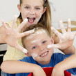 Boy and girl with their hands and faces covered with flour