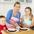 Woman cutting cake, boy and girl smiling at the camera
