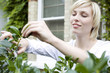 Woman trimming plant with garden scissors