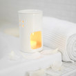 Oil burner and rolled-up towel beside the bathtub