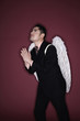 Businessman with angel wings praying while looking up