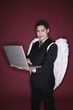 Businessman with angel wings using laptop