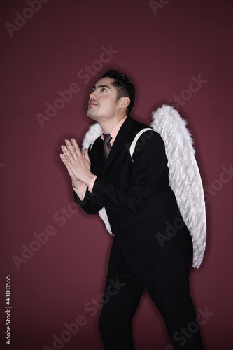 Photo: Businessman with angel wings praying while looking up Businessman with angel wings praying while looking up