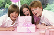 A girl posing with her brothers in front of her birthday presents