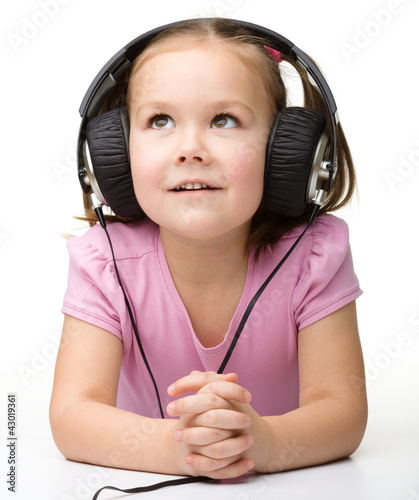 Foto: Cute little girl enjoying music using headphones Cute little girl enjoying music using headphones