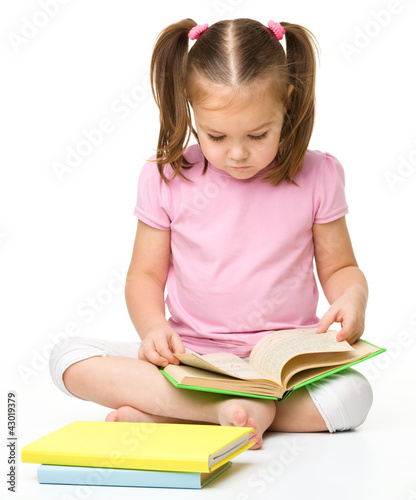 Foto: Cute little girl reads a book Cute little girl reads a book