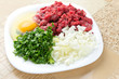 Foto: Chopped onion, minced beef, parsley and an egg on plate Chopped onion, minced beef, parsley and an egg on plate