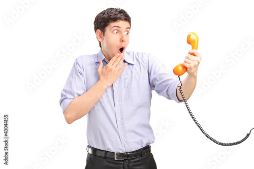 Foto: A shocked man holding a telephone tube A shocked man holding a telephone tube
