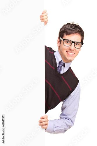 Photo: Smiling handsome male posing behind a blank panel Smiling handsome male posing behind a blank panel