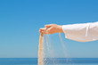 Girl pours sand from his hands. Against the background of the oc