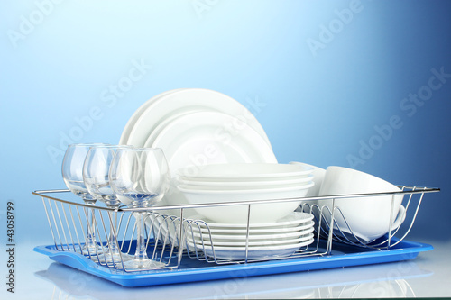 Photo: clean dishes on stand on blue background clean dishes on stand on blue background