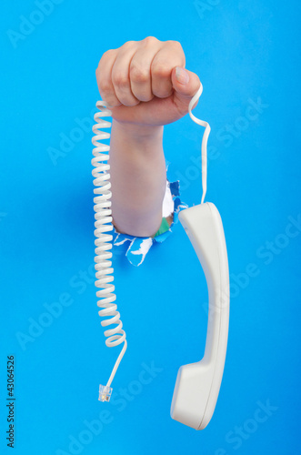 Foto: Hand with phone out of paper hole Hand with phone out of paper hole