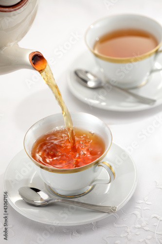 Photo: Pouring tea from the tea pot to the cups Pouring tea from the tea pot to the cups