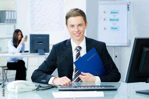 Foto: junger mann im büro mit bewerbungsunterlagen junger mann im büro mit bewerbungsunterlagen