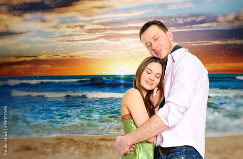 Photo: Portrait of young couple in love embracing at beach and enjoying Portrait of young couple in love embracing at beach and enjoying