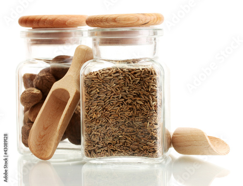 Photo: jars and wooden spoons with nutmeg and cumin isolated on white jars and wooden spoons with nutmeg and cumin isolated on white