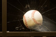 Baseball smashing glass window.