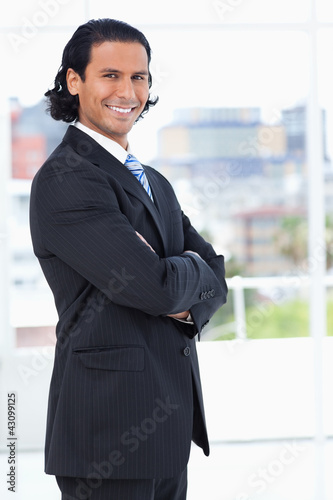 Photo: Smiling executive crossing his arms while looking at the camera Smiling executive crossing his arms while looking at the camera