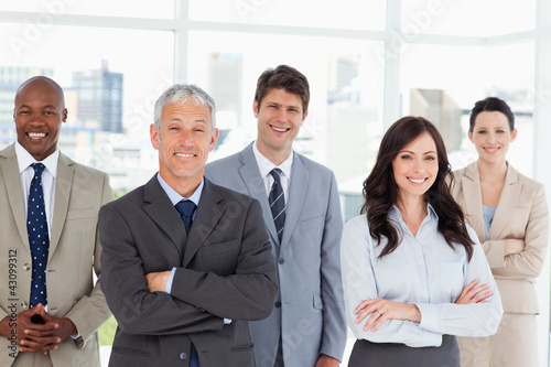 Foto: Five business people crossing their arms in front of a bright wi Five business people crossing their arms in front of a bright wi