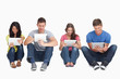 Four friends sitting on the ground all with tablets