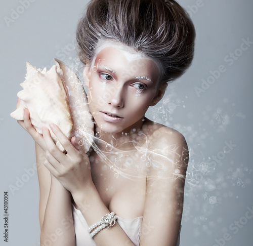 Photo: Beautiful girl with seashell in her hands. Flowing music Beautiful girl with seashell in her hands. Flowing music