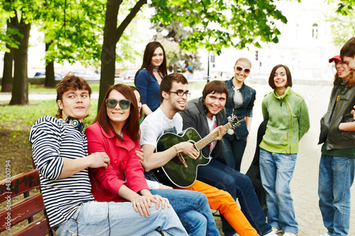 Photo: Group of people in city park listen music. Group of people in city park listen music.