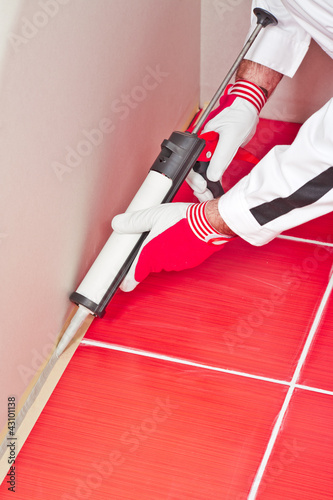 Photo: worker applies silicone sealant on corner wall tiles worker applies silicone sealant on corner wall tiles